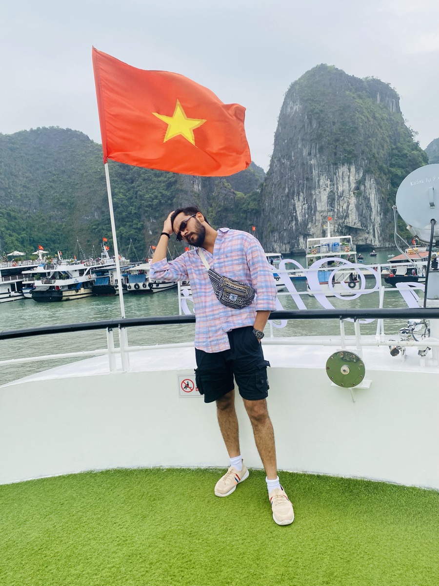 Pratik on a boat deck in Ha Long Bay, Vietnamese flag flying above